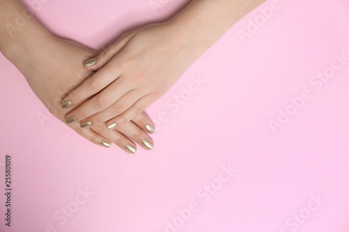 Woman showing golden manicure on color background  top view with space for text. Nail polish trends