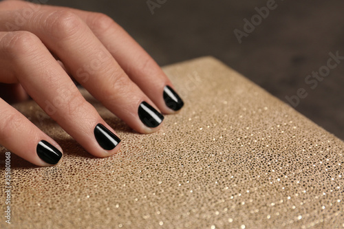 Woman with black manicure holding clutch  closeup. Nail polish trends