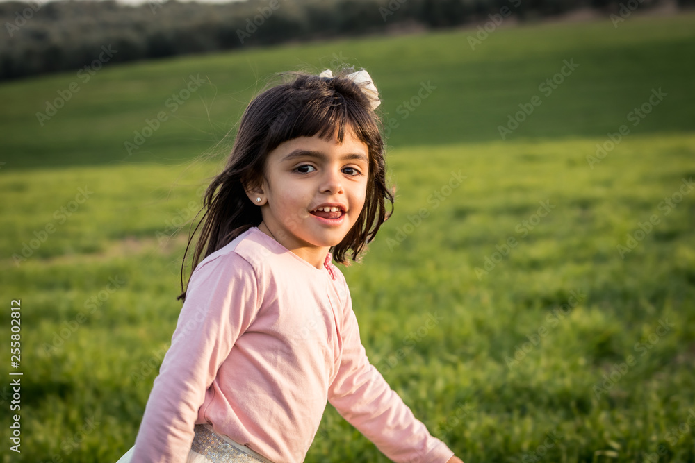 little girl smiling and walking with pink shirt in a meadow little girl smiling and walking with pink shirt in a meadow