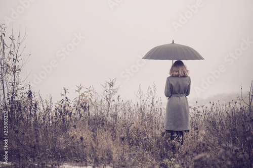 young girl with umbrella in autumn field