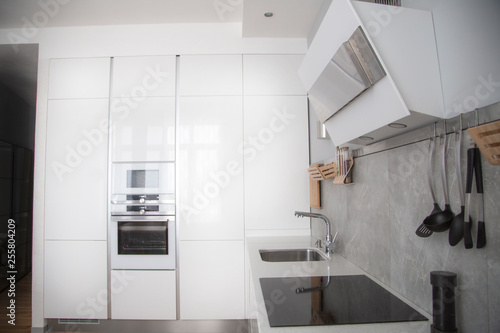 white metal hood in the white kitchen. built-in kitchen in the wall with white applianceswhite metal hood in the white kitchen. built-in kitchen in the wall with white appliances