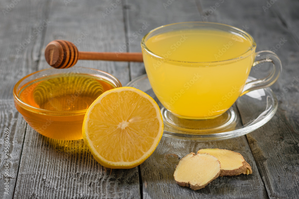 A Cup of ginger root drink and a Cup of honey on a wooden table. A tool to fight viruses. A Cup of ginger root drink and a Cup of honey on a wooden table. A tool to fight viruses.