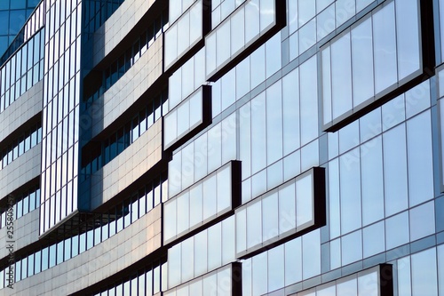 New office building in business center. Wall made of steel and glass with blue sky. 