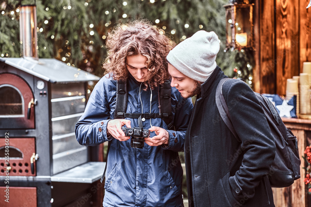 Obraz premium Two Young friends strolling through the Christmas fair with a camera