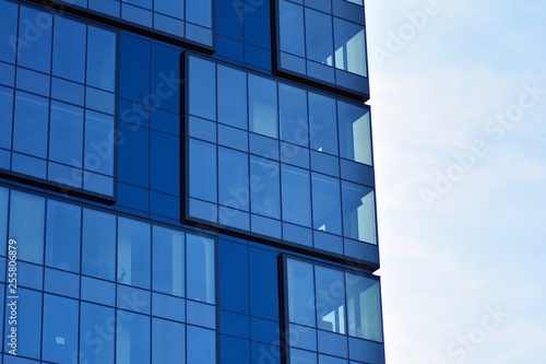 New office building in business center. Wall made of steel and glass with blue sky. 