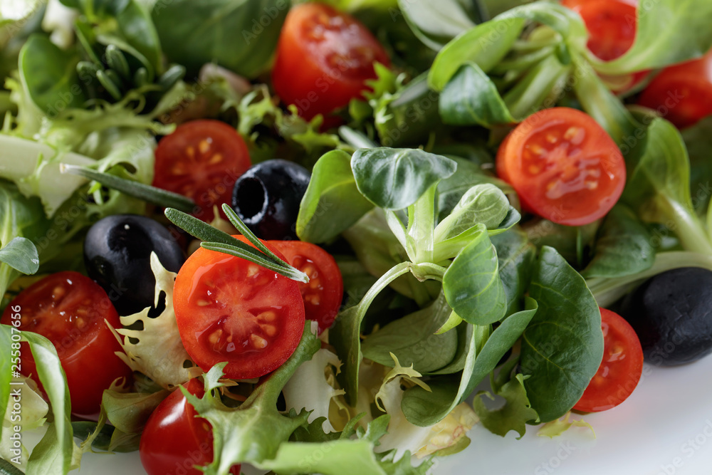 Green salad with tomatoes, rosemary and black olives.