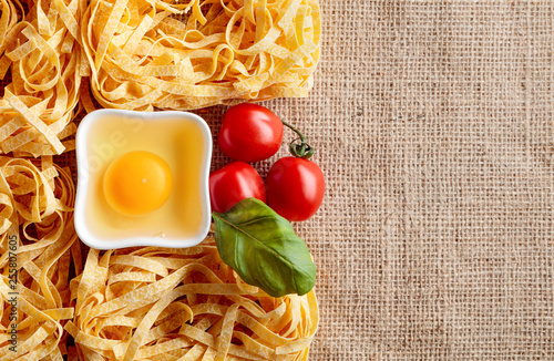 Uncooked egg noodles with tomato and basil.