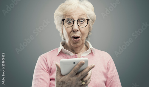Fotografie Happy surprised senior lady using a tablet