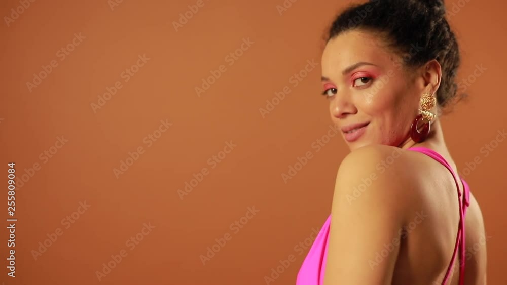 Beautiful woman in pink swimsuit posing in studio at orange background Beautiful woman in pink swimsuit posing in studio at orange background