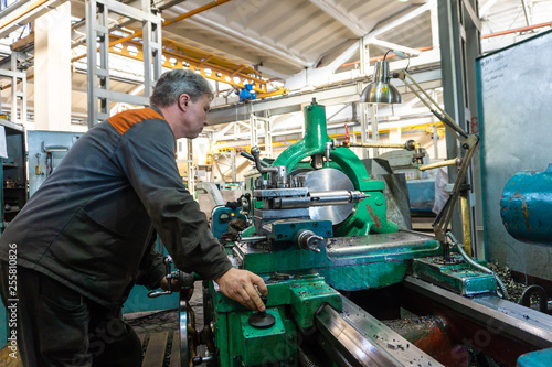 Turner worker manages the metalworking process of mechanical cutting on a lathe.