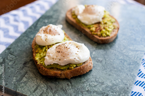 Avocado toast with poached eggs. Served on green marble surface