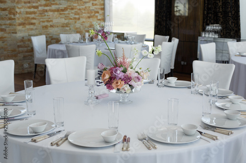 Event white restaurant table served and decorated with delicate fresh flowers