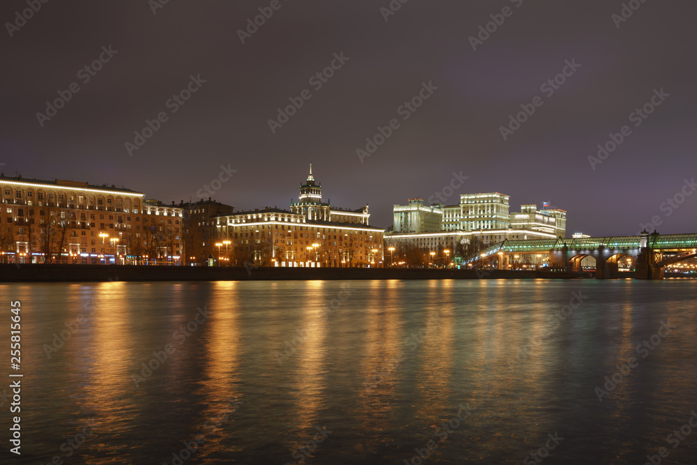 Moskva River, its embankment and Andreevsky (Pushkinsky) pedestrian bridge in the lights reflections at spring night time. Long exposure image.