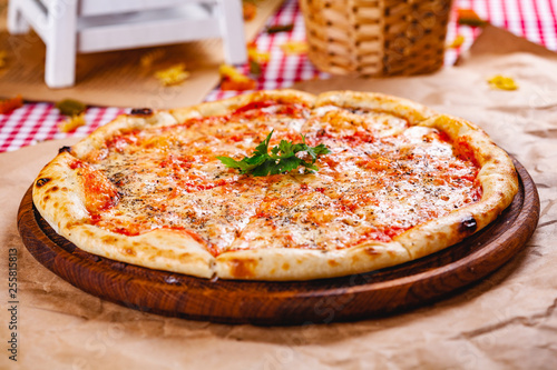Φωτογραφία Italian Pizza Margherita with tomatoes and mozzarella cheese on wooden cutting board