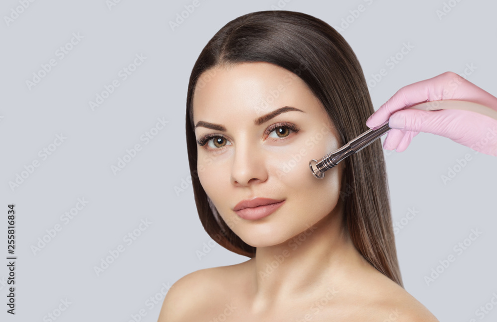 The cosmetologist makes the procedure Microdermabrasion of the facial skin of a beautiful, young woman in a beauty salon.Cosmetology and professional skin care. The cosmetologist makes the procedure Microdermabrasion of the facial skin of a beautiful, young woman in a beauty salon.Cosmetology and professional skin care.