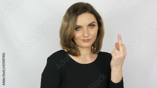 Beautiful sexy bitch girl with flowing hair and blue eyes gently looks into the camera and then shows a fuck sign on a white background. Female aggression. photo