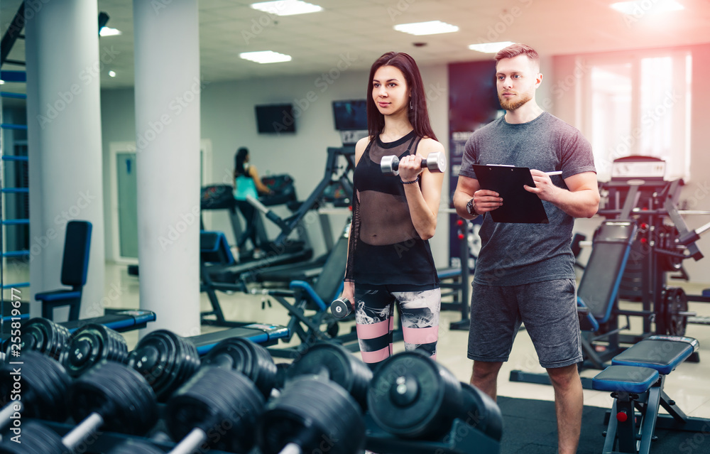 Personal trainer helping woman working with heavy dumbbells. Personal fitness instructor. Personal training. Personal trainer helping woman working with heavy dumbbells. Personal fitness instructor. Personal training.