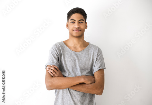 Portrait of an attractive young black man. Handsome afro american boy, teenager. Smiling guy with his hands on his chest on a white background.  photo