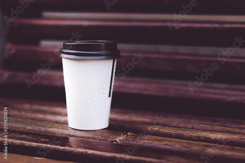 Coffee to go cup behind on a wooden bench