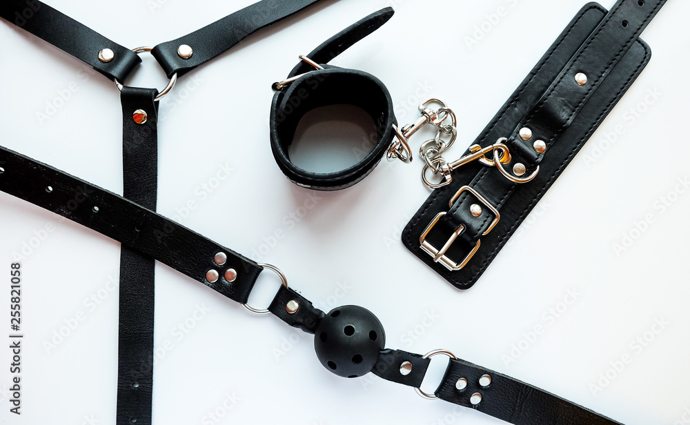 BDSM black leather sex attributes: handcuffs, sex toy, ball gag, leather  belt Stock Photo | Adobe Stock