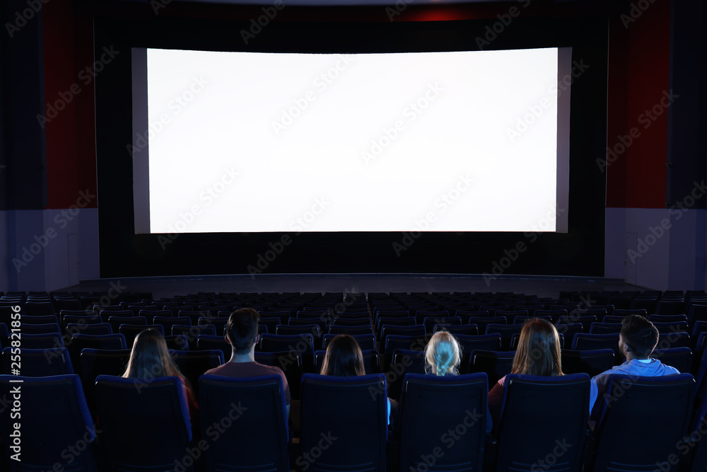 Obraz premium Young people watching movie in cinema theatre. Space for text