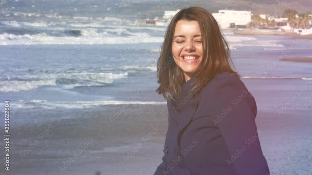 Happy woman full of joy smiling looking camera in front of the ocean in spring slow motion
