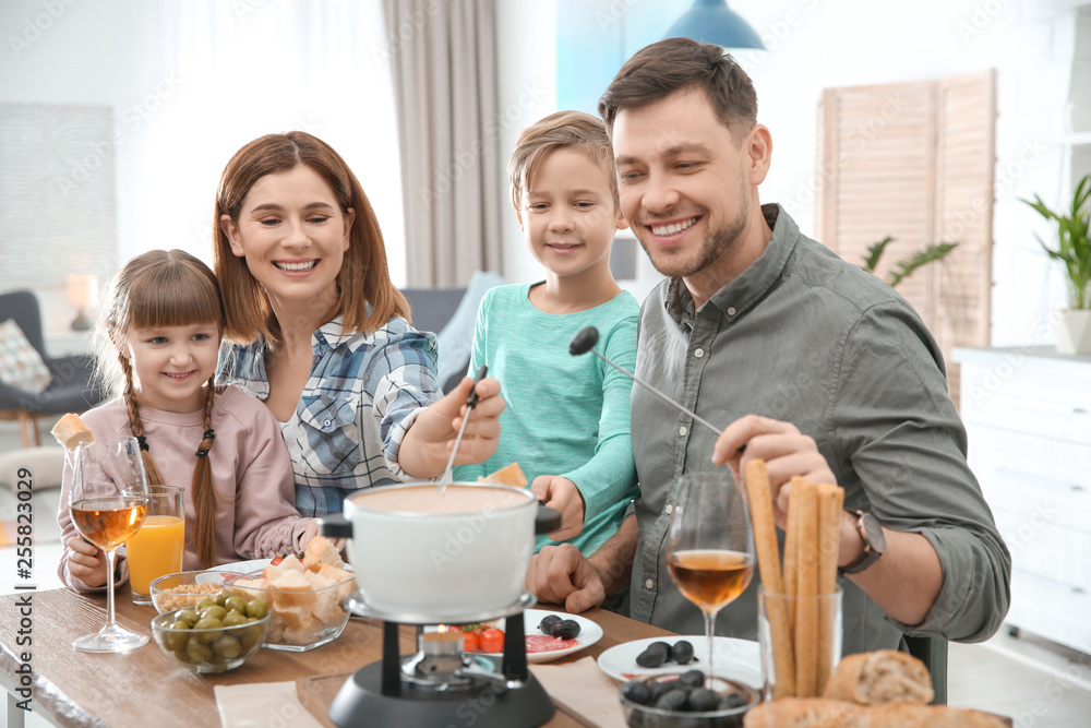 Happy family enjoying fondue dinner at home Happy family enjoying fondue dinner at home