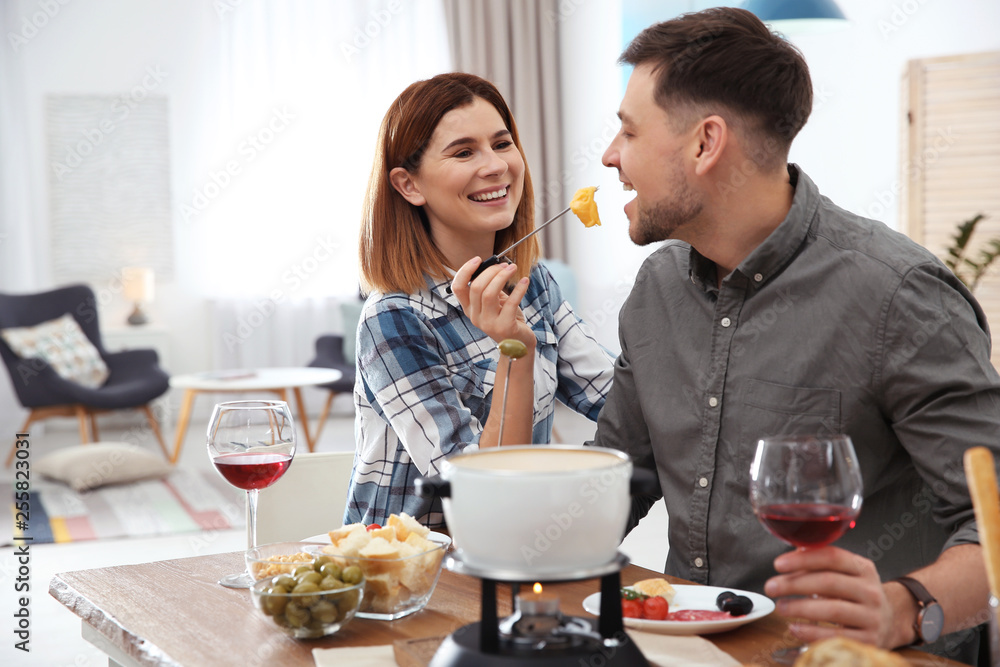 Happy couple enjoying fondue dinner at home Happy couple enjoying fondue dinner at home
