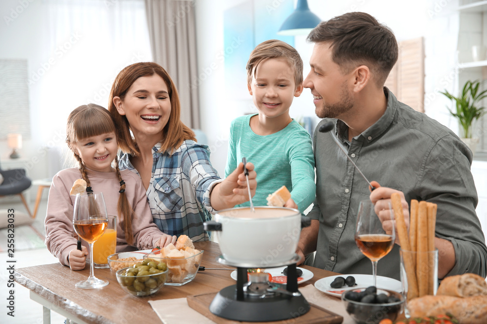 Happy family enjoying fondue dinner at home Happy family enjoying fondue dinner at home