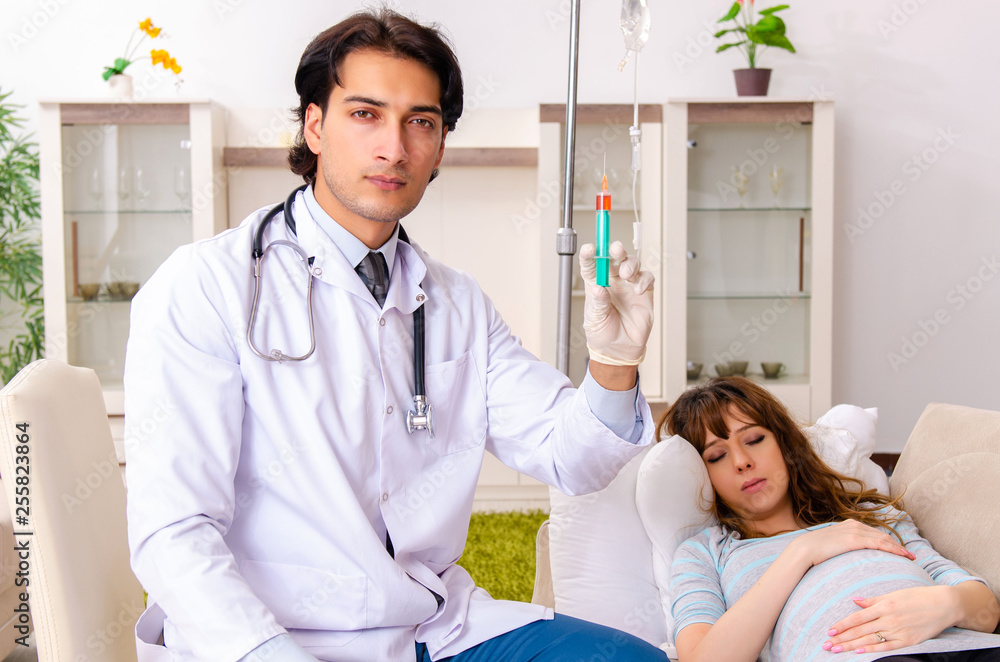 Young handsome doctor visiting pregnant woman at home 