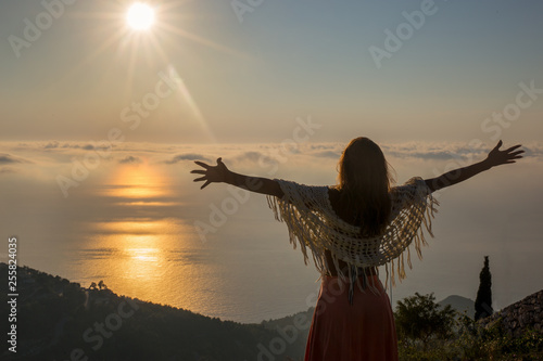 Beautiful young woman spreading her arms into the sunset towards the ocean © Marko