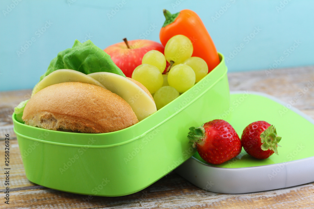 Healthy school lunch box containing cheese sandwich, crunchy yellow pepper and fresh fruit: apple, strawberries and grapes Healthy school lunch box containing cheese sandwich, crunchy yellow pepper and fresh fruit: apple, strawberries and grapes