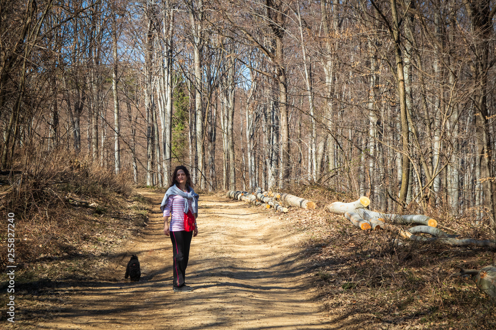 Woman walking in the forest with small poodle dog Woman walking in the forest with small poodle dog