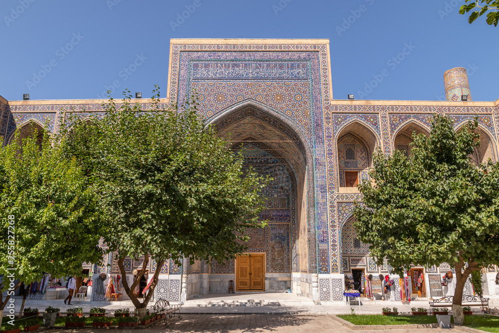 The Ulugh Beg madrasah view from the yard.  In the courtyard of the Madrasah with trees. Inside the Madrasah on Registan square in Samarkand. Ancient Madrasah in Uzbekistan. Sunny summer day.