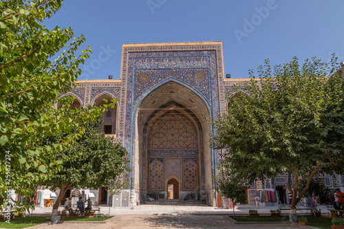 The Ulugh Beg madrasah view from the yard. In the courtyard of the Madrasah with trees. Inside the Madrasah on Registan square in Samarkand. Ancient Madrasah in Uzbekistan. Sunny summer day.