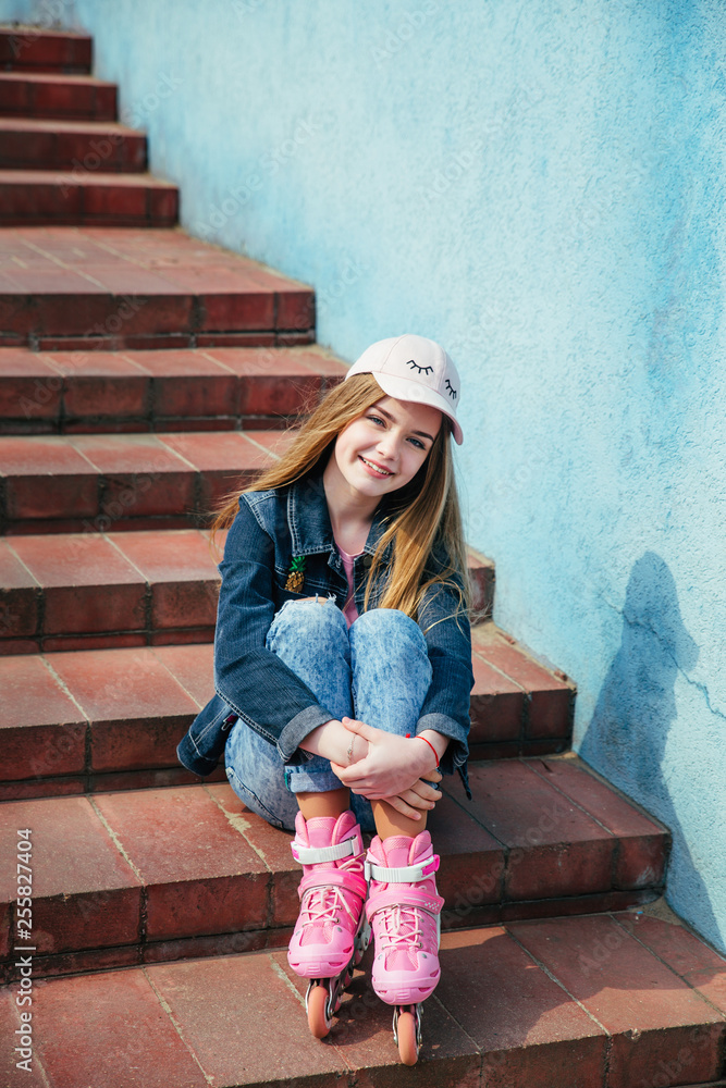 Teenager skating in city . Girl going rollerblading sitting on step Teenager skating in city . Girl going rollerblading sitting on step