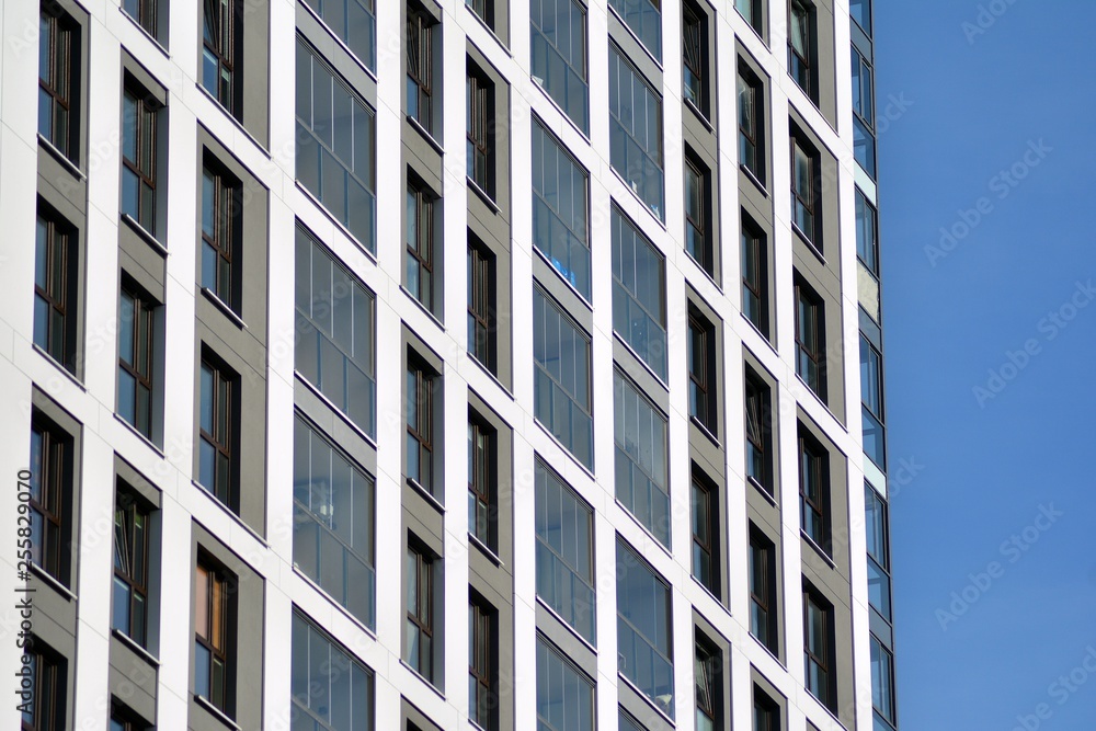 Multistory new modern apartment building. Stylish living block of flats. Modern, new executive apartments and with deep blue summer sky Multistory new modern apartment building. Stylish living block of flats. Modern, new executive apartments and with deep blue summer sky