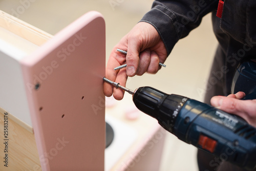 Carpenter working on play furniture. Tightening screws with screwdriver