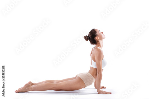 Portrait of gorgeous young woman practicing yoga. Beautiful girl practice cobra asana isolated on white.