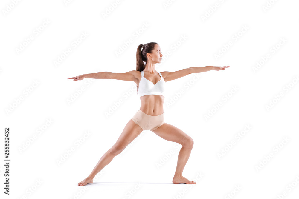 Attractive young woman doing yoga exercise Virabhadrasana, isolated on white background.