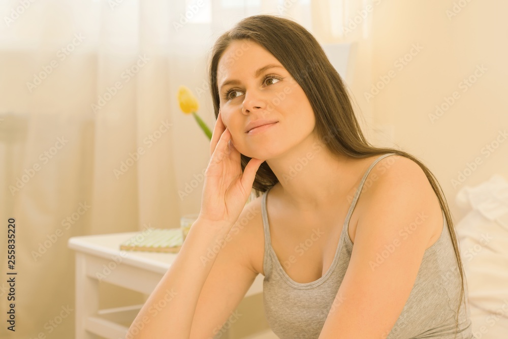 Portrait of young romantic beautiful brunette woman sitting at home in bed, woman is dreamily looking away, sunny bedroom interior. Portrait of young romantic beautiful brunette woman sitting at home in bed, woman is dreamily looking away, sunny bedroom interior.