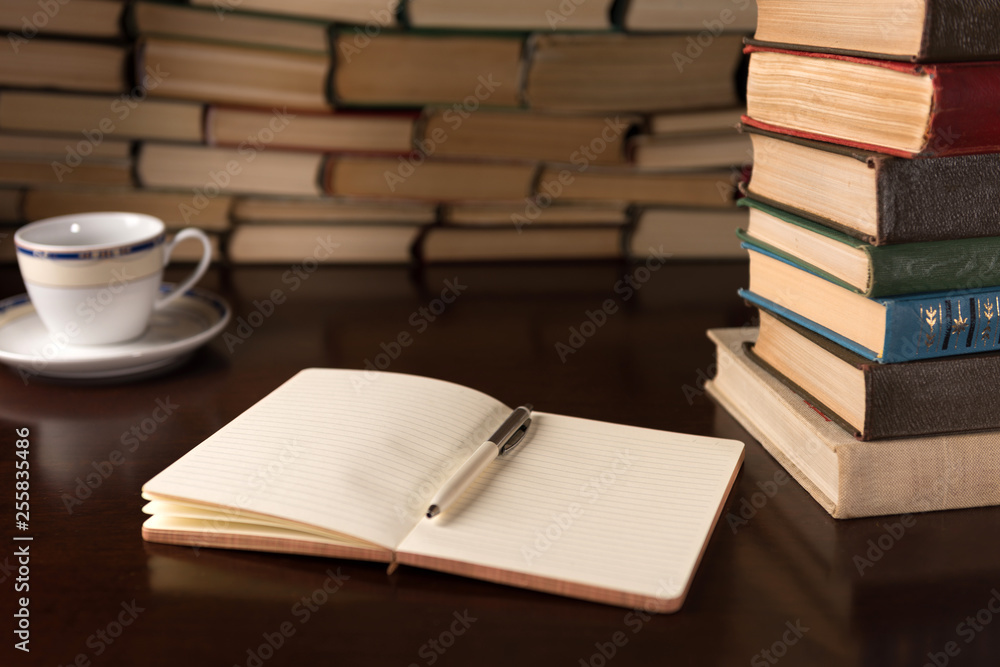 open notebook and cup on the background of books open notebook and cup on the background of books