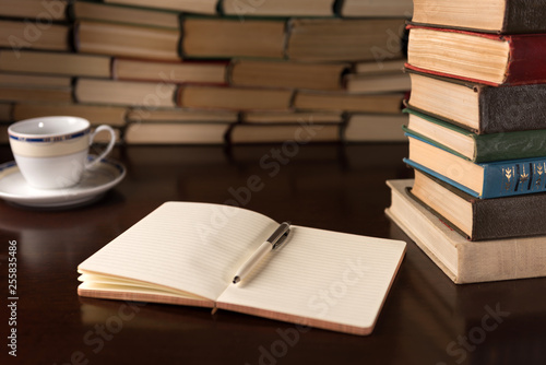 open notebook and cup on the background of books