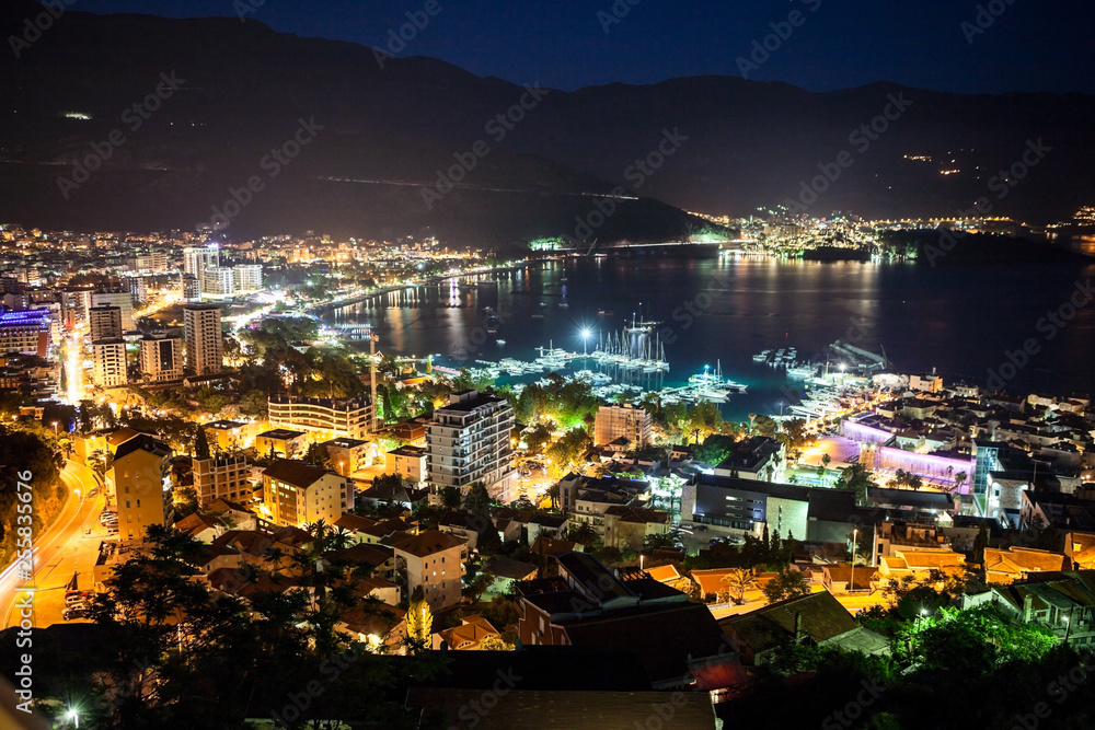 Aerial view at night colorful Budva city. The central modern part with sea shore and port in Budvanska riviera. Montenegro, Europe