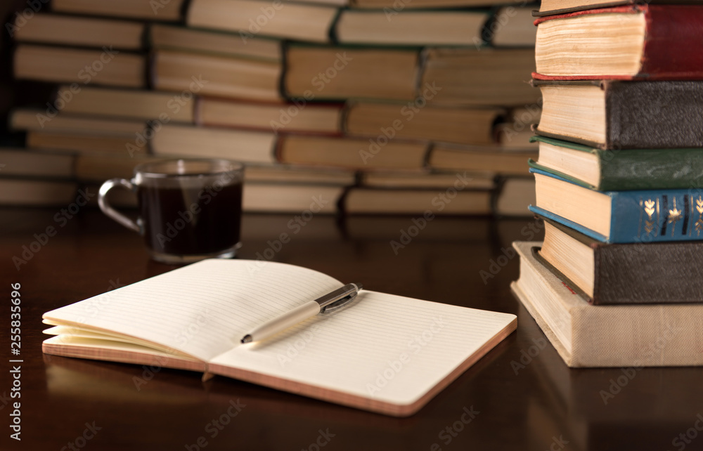 Fototapeta premium open notebook and cup on the background of books