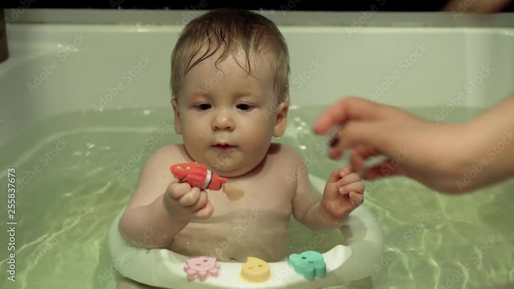 child bathes in the bathroom, plays with electronic fish, mother takes the toy from him. child bathes in the bathroom, plays with electronic fish, mother takes the toy from him.