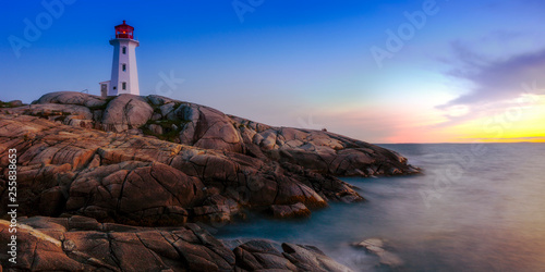 Beautiful Peggy Cove Light House with Sunset, Nova Scotia, Canada. Photo shows couple watching sunset.