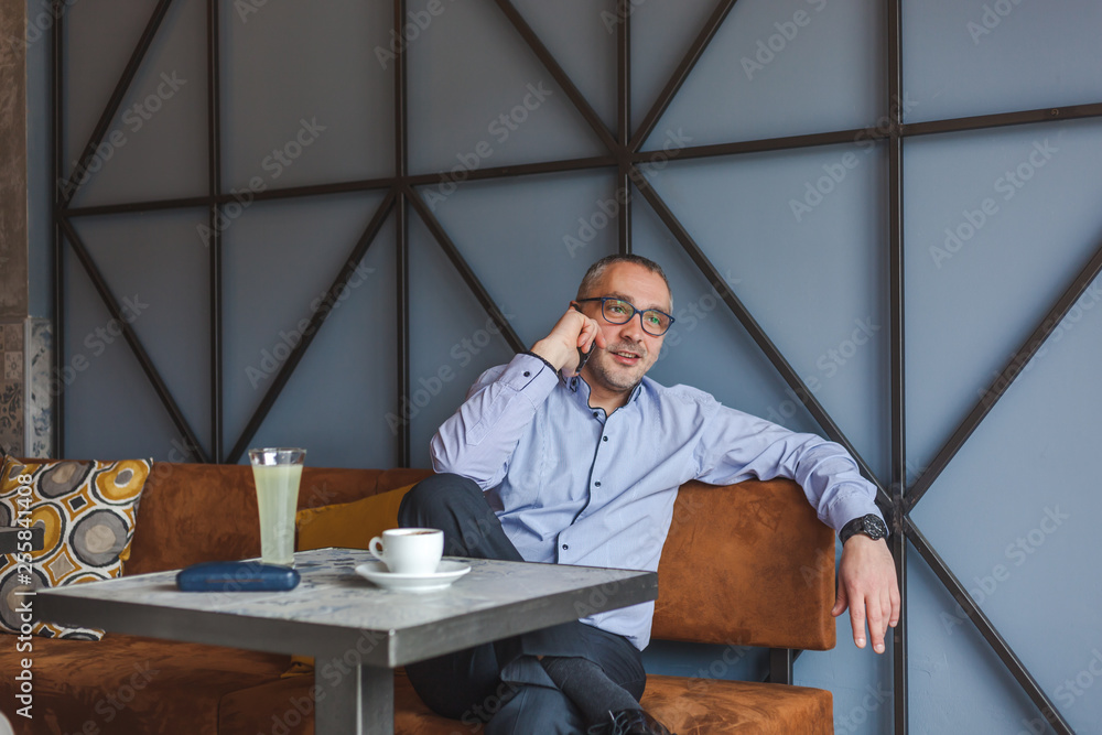 Middle aged businessman talking on the phone in cafe Middle aged businessman talking on the phone in cafe