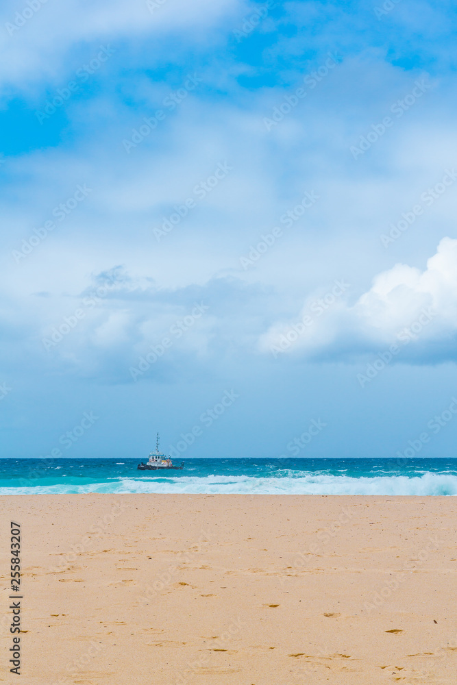 idyllic seaside landscape during sunny day, beautiful intense colours, small boat on the horizon