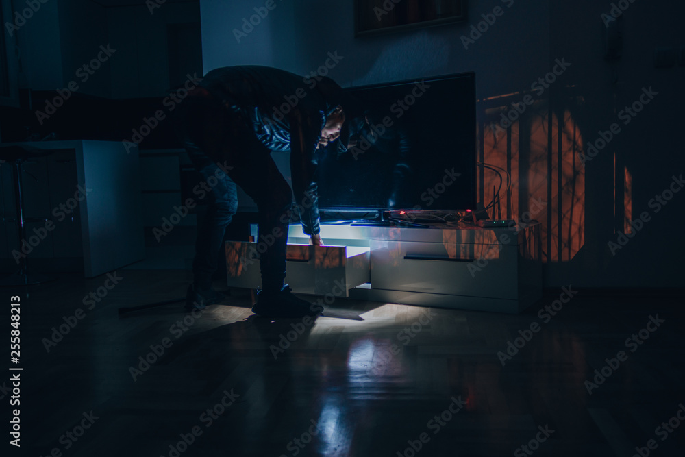 Young thief walk in the apartment and stealing from the desk Young thief walk in the apartment and stealing from the desk